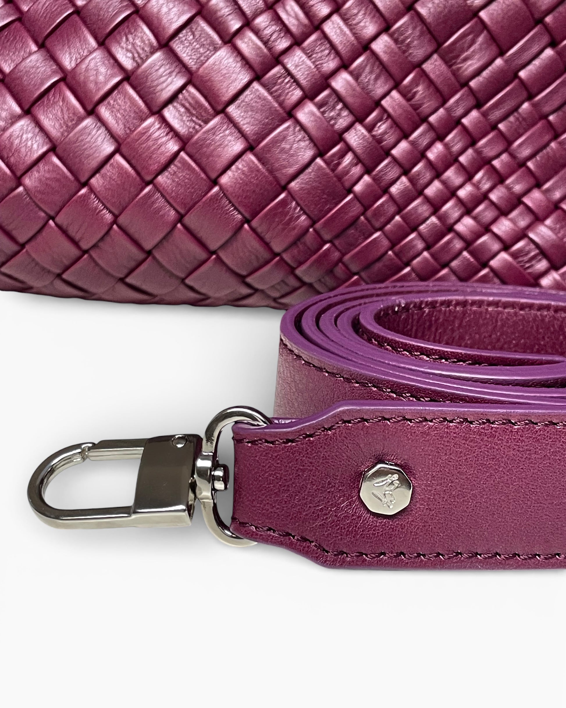 Close-up of a purple woven handbag with a matching strap on a white background