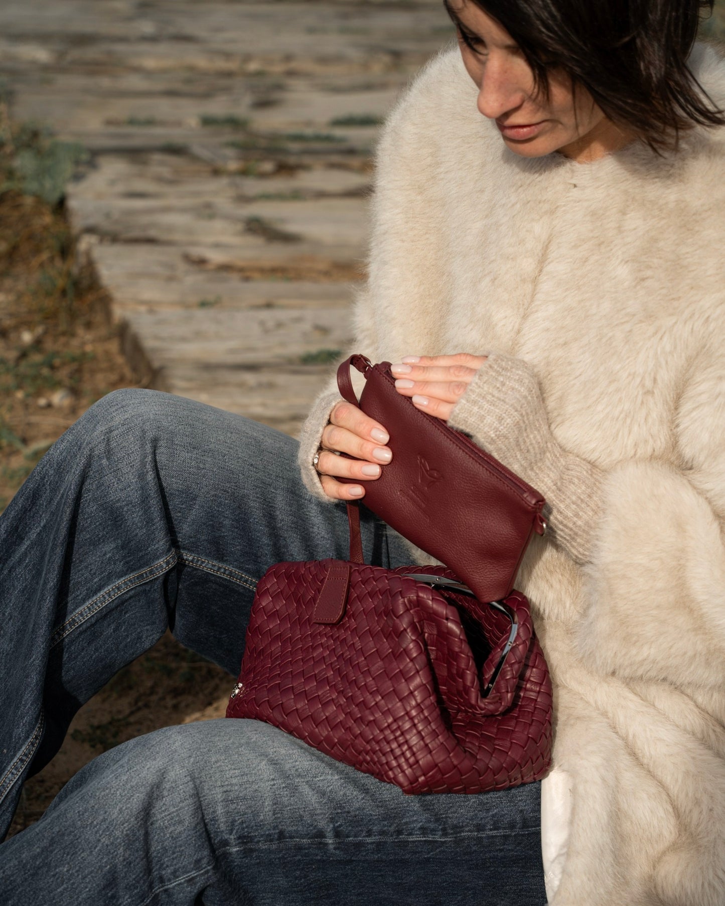 Woman holding a maroon handbag outdoors
