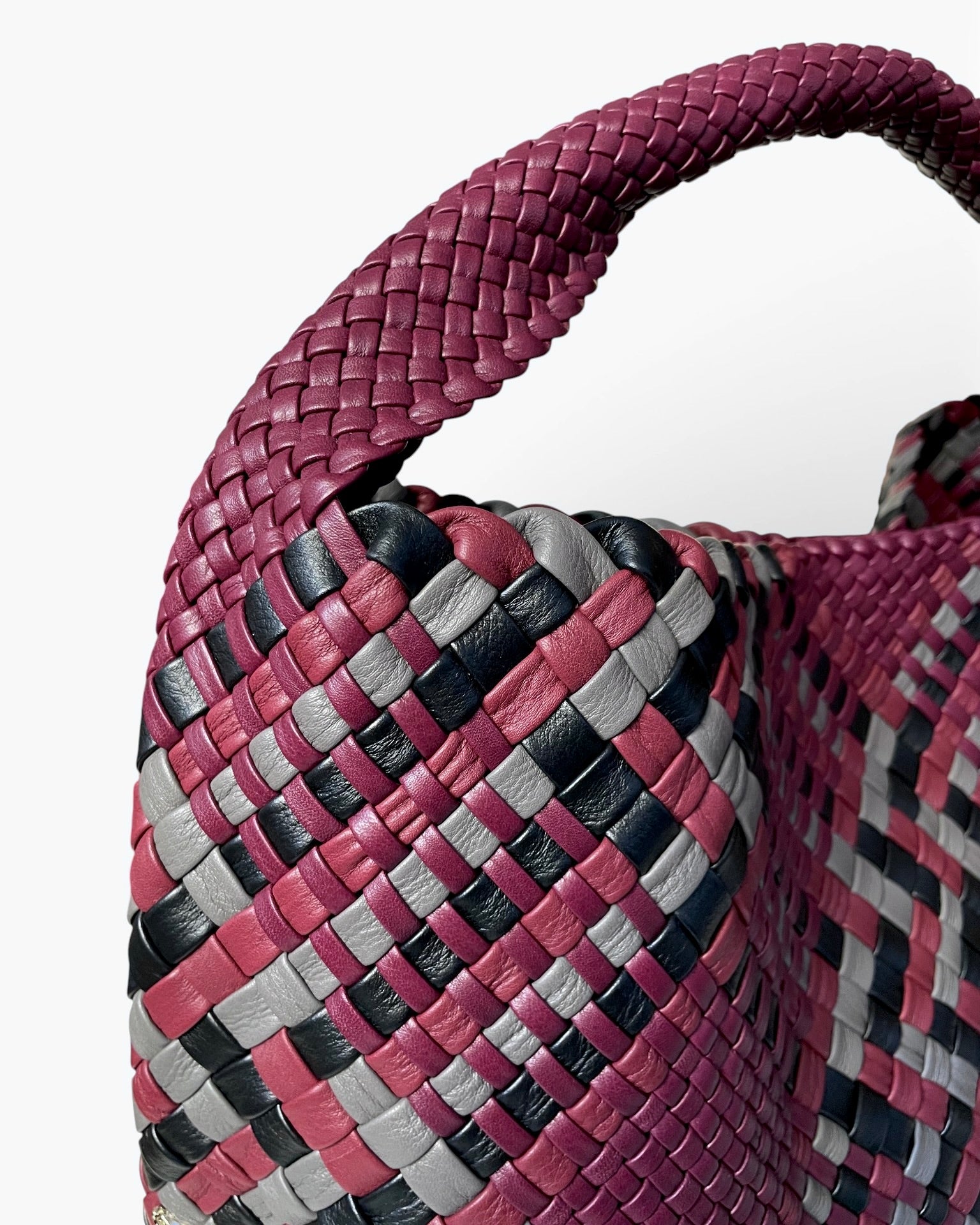 Close-up of a woven leather bag with a multicolor pattern on a white background