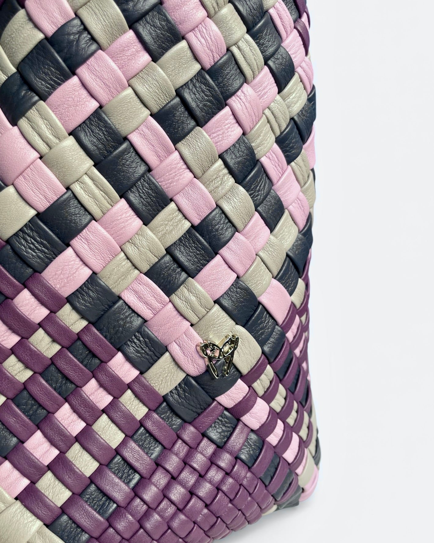 Close-up of a woven leather bag with a checkered pattern on a light gray background
