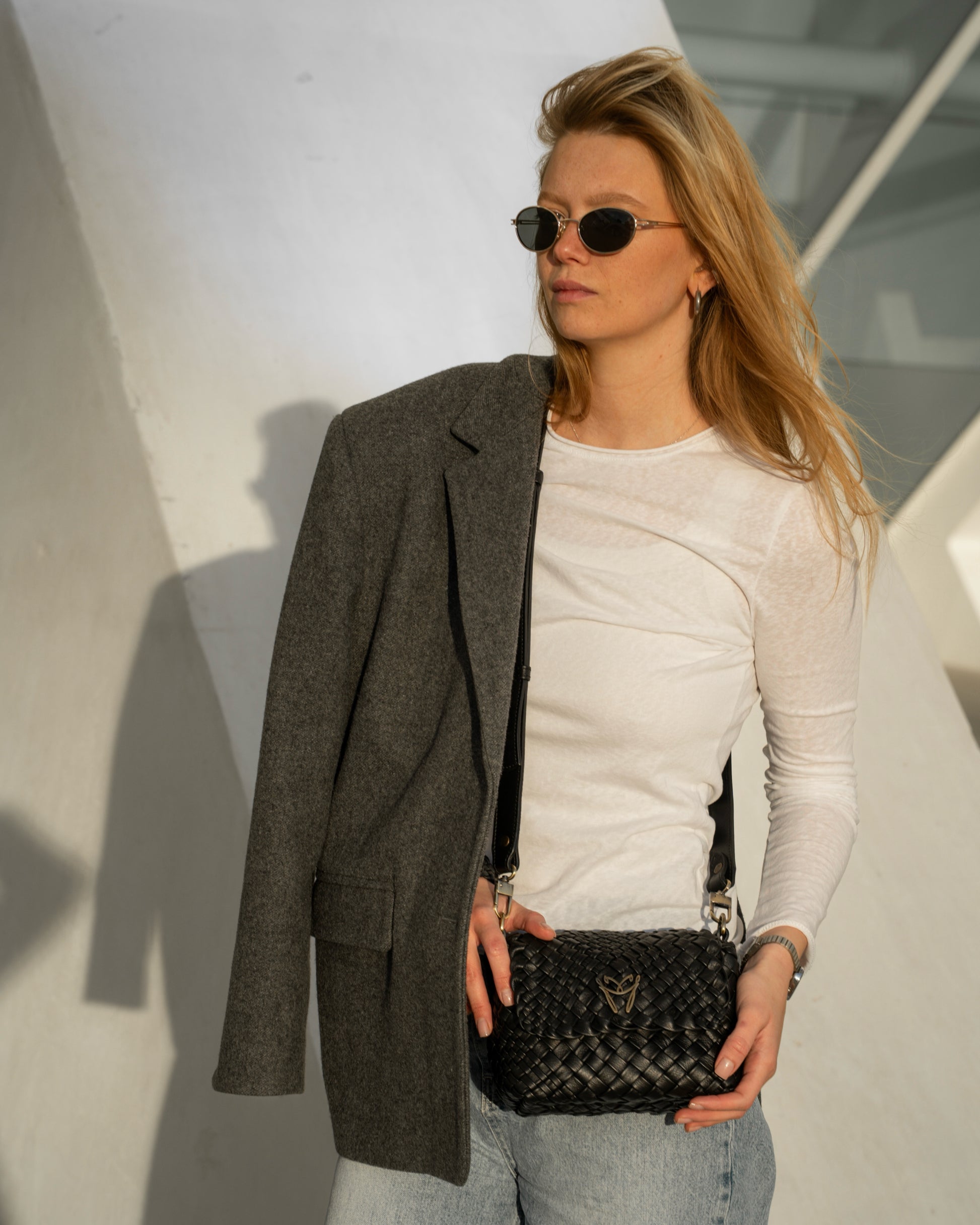 Woman holding a black handbag against a light background