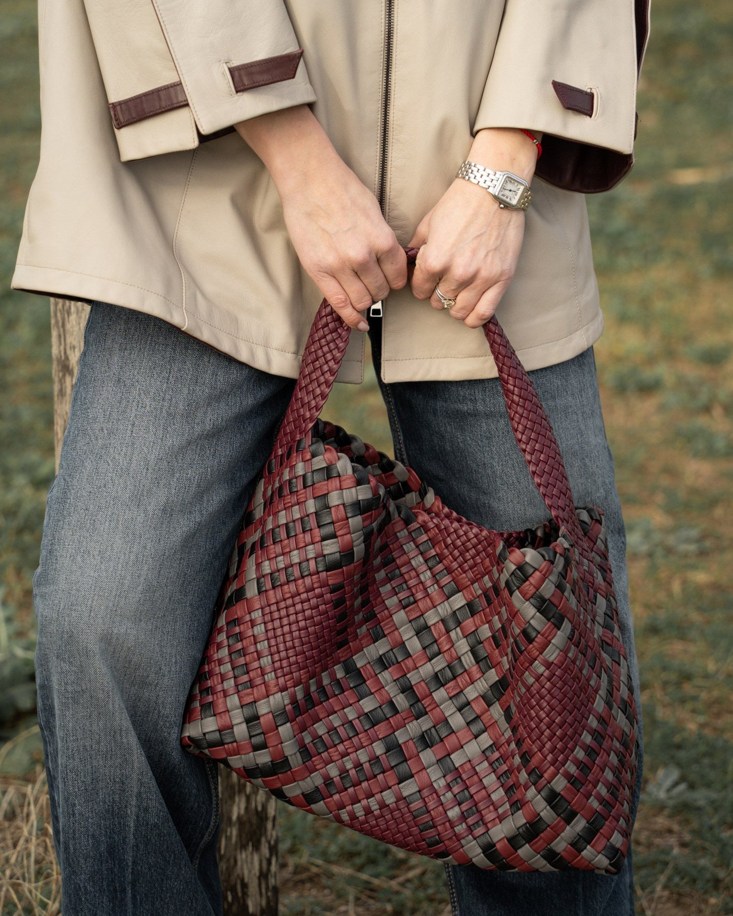 Person holding a plaid bag outdoors