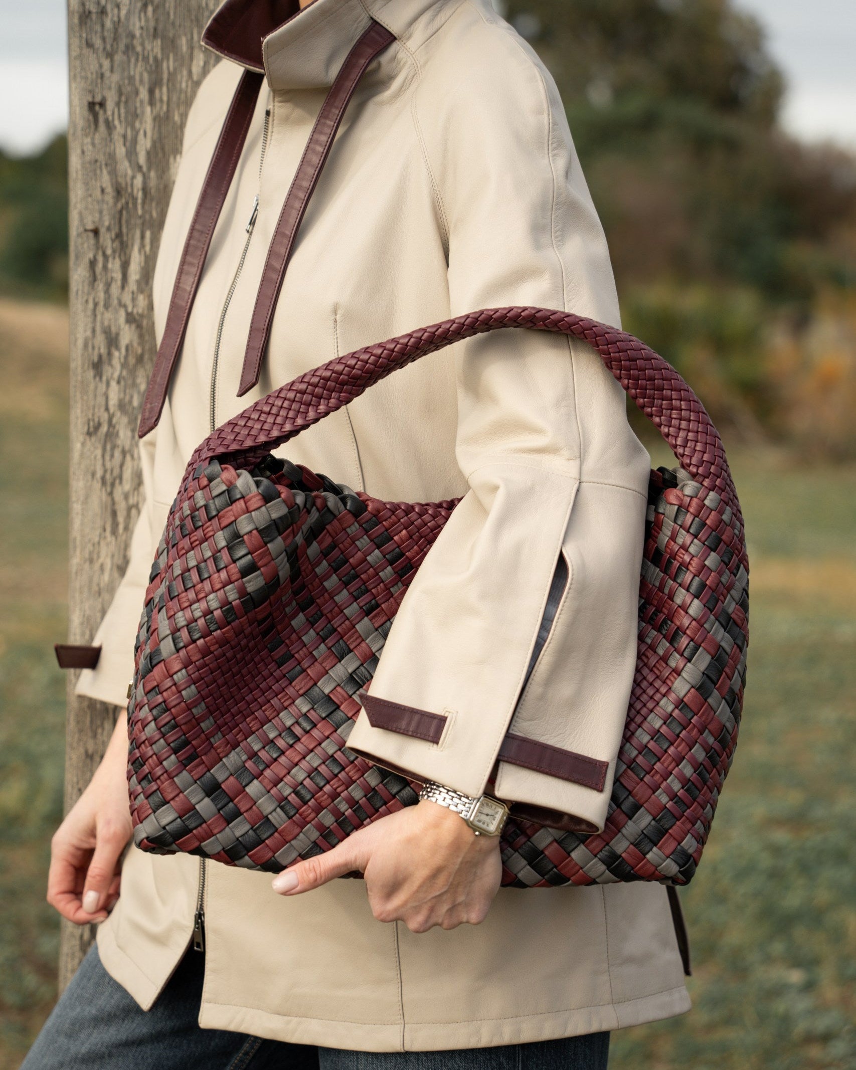 Person holding a plaid bag outdoors with a natural background